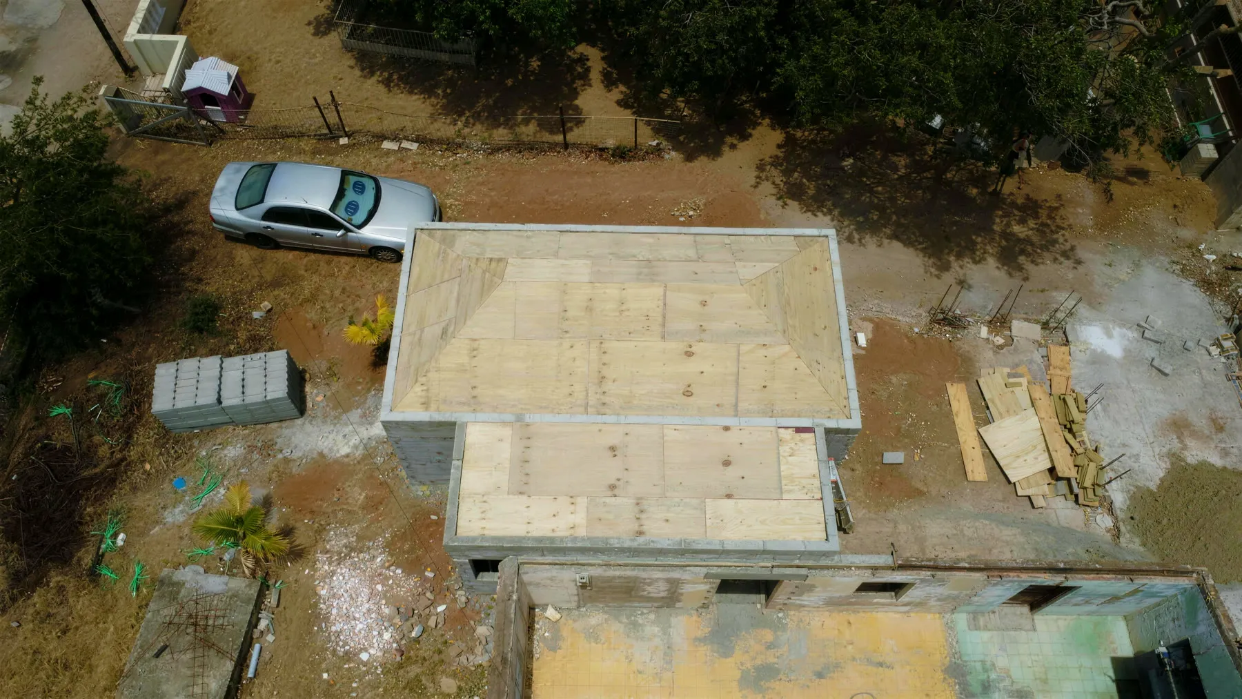 New roof under construction from above — fresh plywood decking over framing, Optimo crew on site