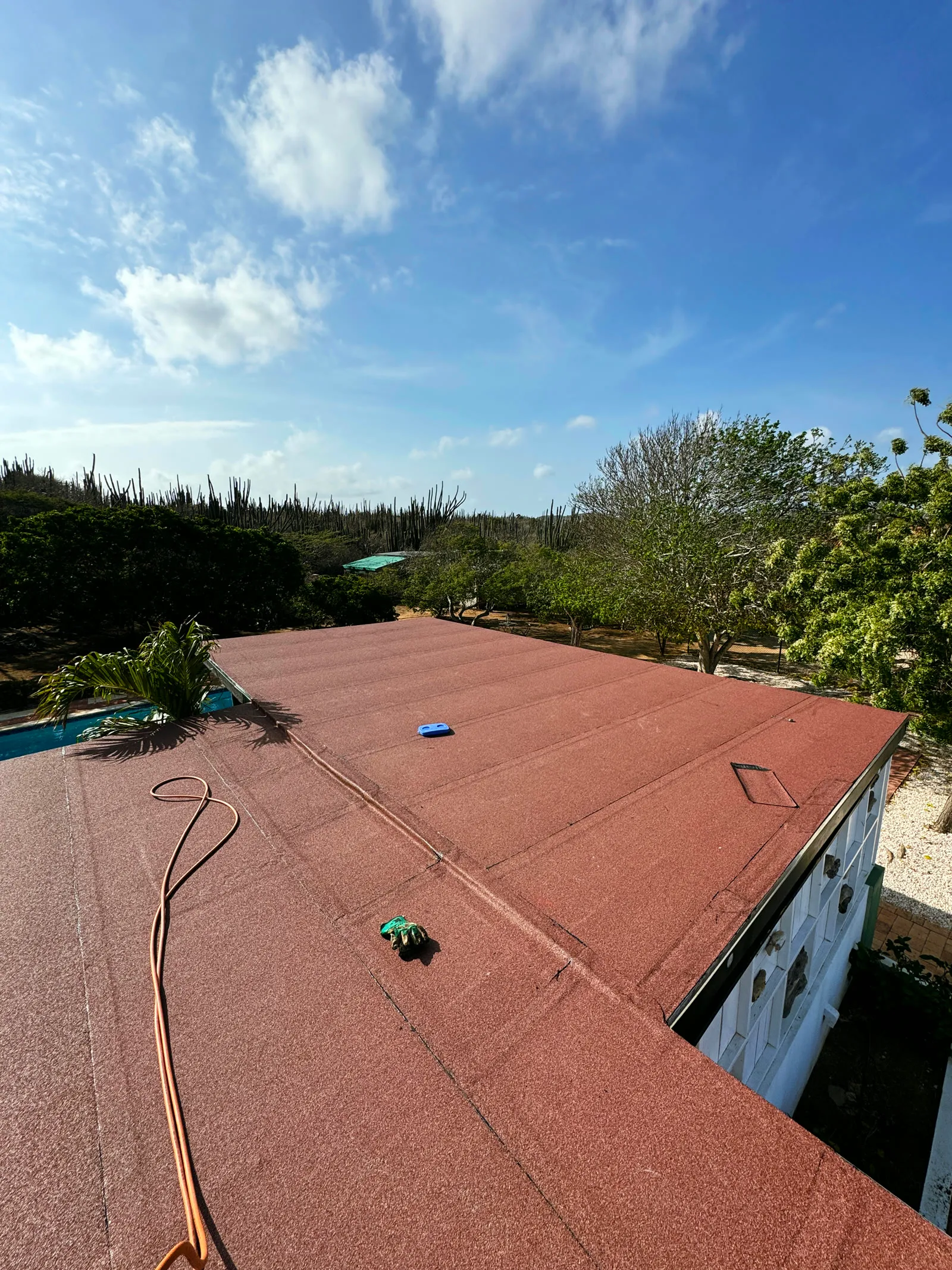 Finished red mineral torch-on membrane flat roof under a blue Aruba sky