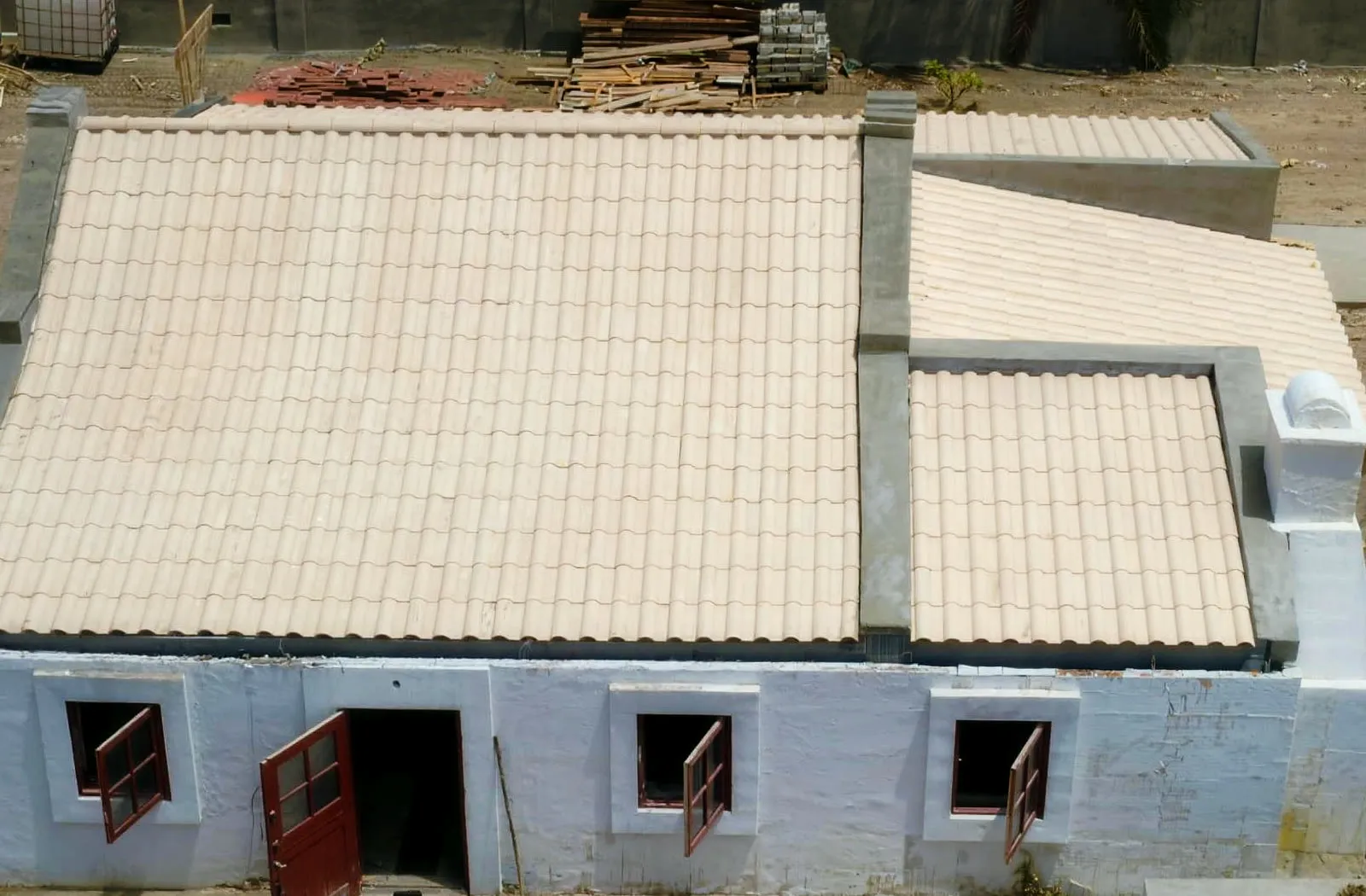Freshly tiled roof on a traditional Aruba house — new sand-colored tile courses, drone view